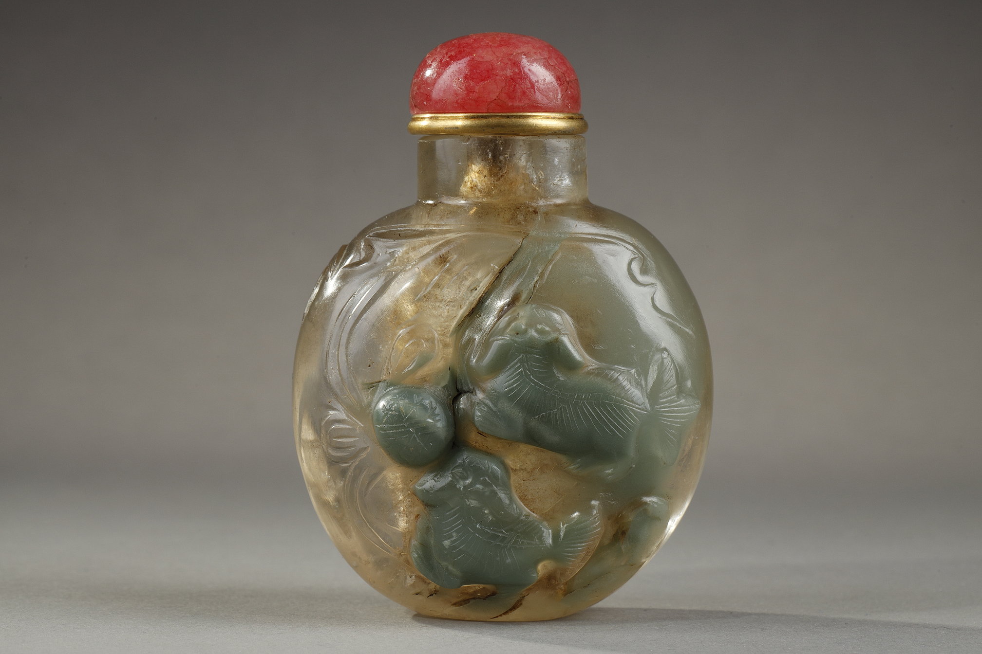 Chinese rock crystal snuff bottle carved with two Fo dogs playing with a brocade ball in a green vein . and other side with a bird   - circa 1770/1850       H 6,9cm